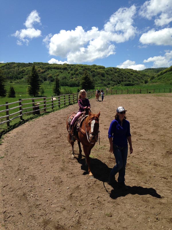 mom leading daughter on horseback