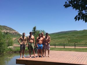 men on dock at lake in swim trunks