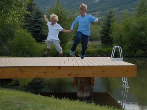 boys jumping from a dock into a lake smiling